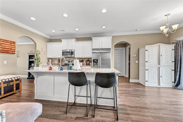 477 Caballo St, Farmington, AR 72730 - kitchen with appliances with stainless steel finishes, arched walkways, ornamental molding, a breakfast bar area, and backsplash