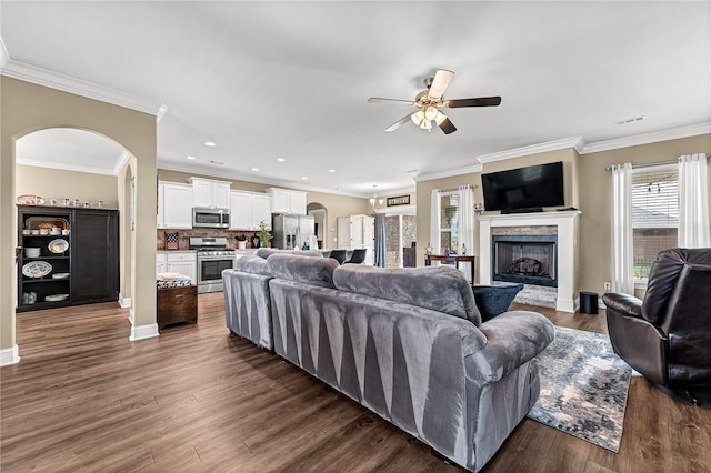477 Caballo St, Farmington, AR 72730 - living room featuring ceiling fan, arched walkways, dark wood finished floors, crown molding, and a fireplace