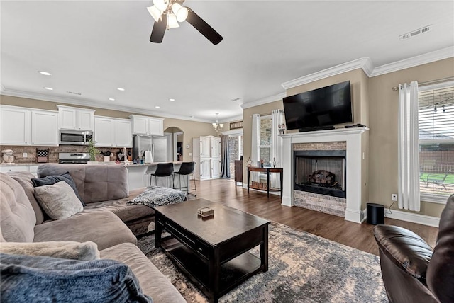 477 Caballo St, Farmington, AR 72730 - living room featuring ceiling fan, ornamental molding, a fireplace, dark wood-type flooring, and arched walkways