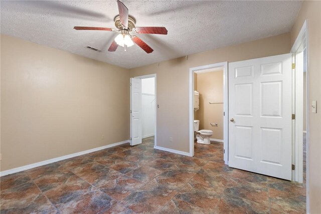 17 Pivot Rock Rd Unit 5, Eureka Springs, AR 72632 - unfurnished bedroom with a textured ceiling, stone finish flooring, a walk in closet, connected bathroom, and a ceiling fan