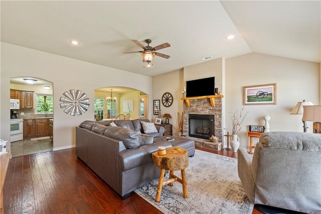 950 Nemett Cir, Pea Ridge, AR 72751 - living room with arched walkways, a ceiling fan, dark wood-type flooring, a stone fireplace, and a chandelier