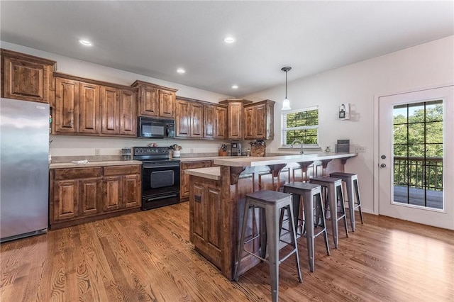 21 Cherhill Dr, Bella Vista, AR 72714 - kitchen with black appliances, a kitchen breakfast bar, wood finished floors, light countertops, and recessed lighting