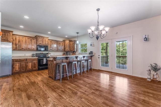 21 Cherhill Dr, Bella Vista, AR 72714 - kitchen with black appliances, brown cabinets, wood finished floors, a chandelier, and a kitchen bar