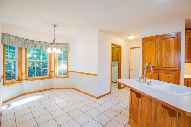 16 Penrith Dr, Bella Vista, AR 72714 - kitchen featuring hanging light fixtures, brown cabinets, light countertops, and light tile patterned floors