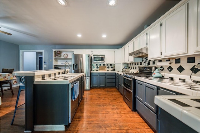 21569 Sibley Rd, Sulphur Springs, AR 72768 - kitchen with stainless steel appliances, tile countertops, under cabinet range hood, white cabinets, and backsplash