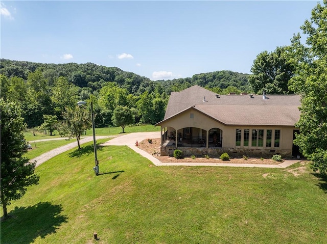 21569 Sibley Rd, Sulphur Springs, AR 72768 - view of front of house featuring a front yard, a wooded view, driveway, and a shingled roof