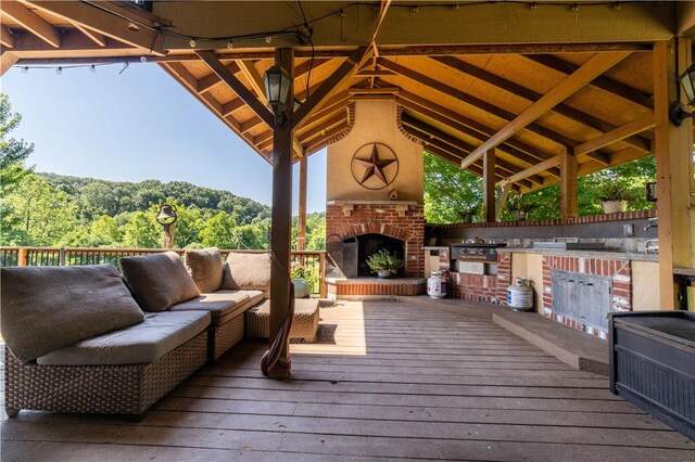 21569 Sibley Rd, Sulphur Springs, AR 72768 - deck featuring area for grilling, an outdoor living space with a fireplace, and a wooded view
