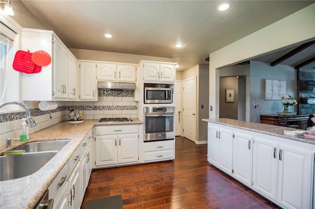 704 NW 8th St, Bentonville, AR 72712 - kitchen featuring stainless steel appliances, dark wood-style flooring, decorative backsplash, white cabinets, and a textured ceiling