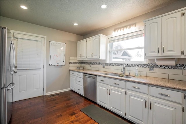 704 NW 8th St, Bentonville, AR 72712 - kitchen with stainless steel appliances, a textured ceiling, decorative backsplash, white cabinets, and dark wood-type flooring