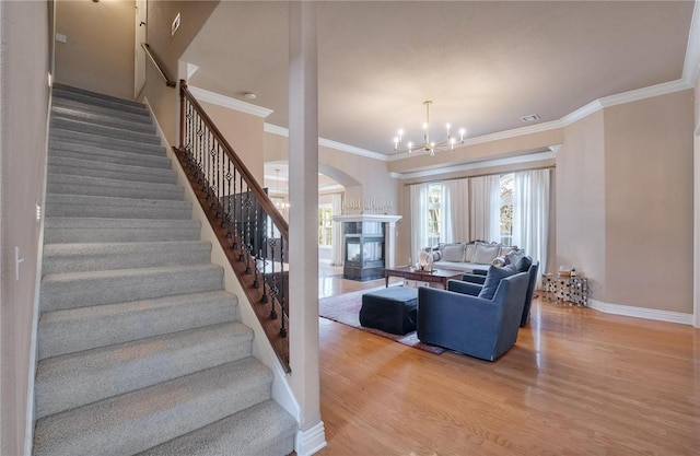 1531 Partridge Run, Bentonville, AR 72713 - living room featuring a glass covered fireplace, stairway, wood finished floors, a chandelier, and crown molding