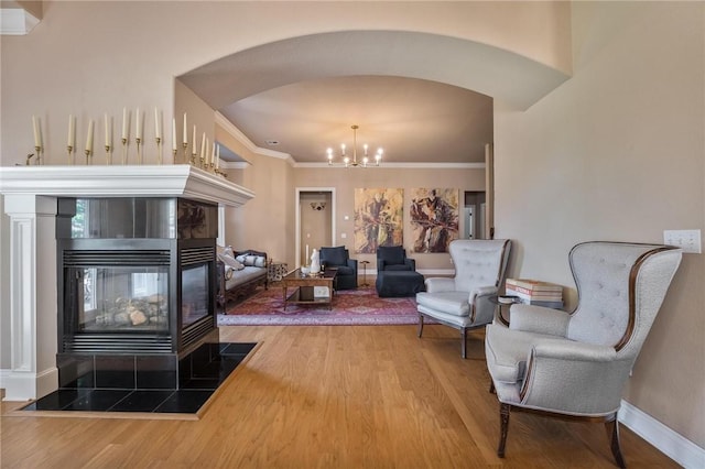 1531 Partridge Run, Bentonville, AR 72713 - living area with arched walkways, wood finished floors, a chandelier, crown molding, and a tile fireplace