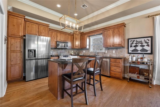 1531 Partridge Run, Bentonville, AR 72713 - kitchen with stainless steel appliances, brown cabinetry, a center island, backsplash, and ornamental molding
