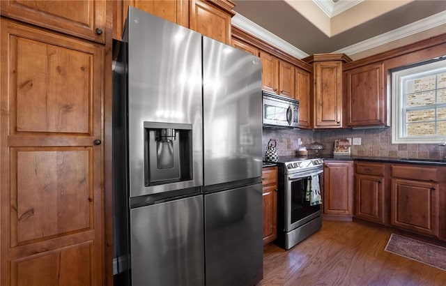1531 Partridge Run, Bentonville, AR 72713 - kitchen with stainless steel appliances, dark countertops, brown cabinets, ornamental molding, and dark wood-style floors