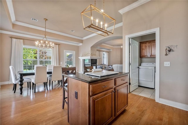 1531 Partridge Run, Bentonville, AR 72713 - kitchen featuring washer / dryer, a chandelier, arched walkways, light wood-style flooring, and a breakfast bar area