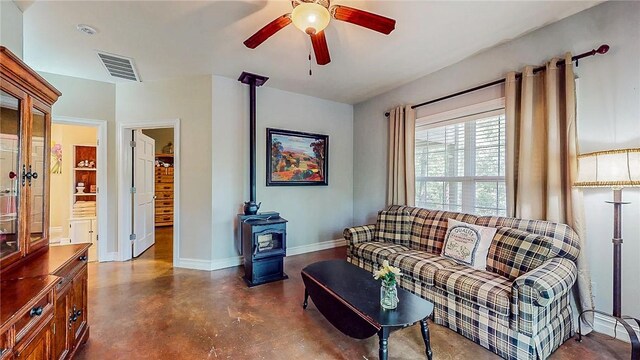 19641 Conestoga Rd, Elkins, AR 72727 - living room featuring a wood stove, concrete flooring, and ceiling fan