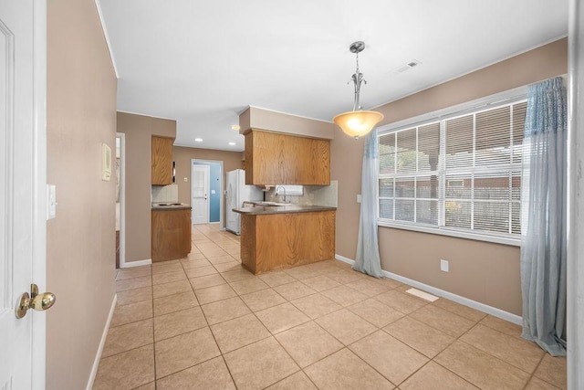2001 Pin Oak Dr, Springdale, AR 72762 - kitchen with brown cabinetry, freestanding refrigerator, light tile patterned flooring, a peninsula, and pendant lighting