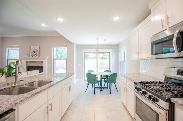 7655 Longspur Ave, Springdale, AR 72762 - kitchen featuring appliances with stainless steel finishes, backsplash, white cabinets, a brick fireplace, and recessed lighting