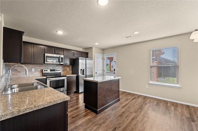 2504 Maplewood Ave, Lowell, AR 72745 - kitchen with stainless steel appliances, a center island, wood finished floors, dark brown cabinetry, and a textured ceiling