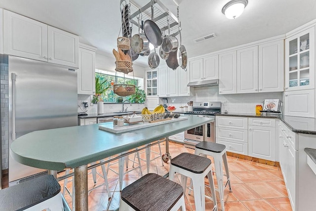 3389 Madison Unit 2405, Huntsville, AR 72740 - kitchen with appliances with stainless steel finishes, tasteful backsplash, white cabinets, dark countertops, and glass insert cabinets