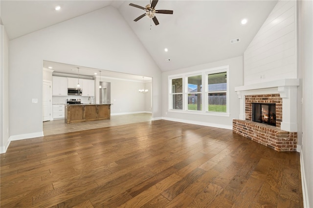 1052 Morra Ave, Tontitown, AR 72762 - unfurnished living room with high vaulted ceiling, a ceiling fan, wood-type flooring, a fireplace, and recessed lighting