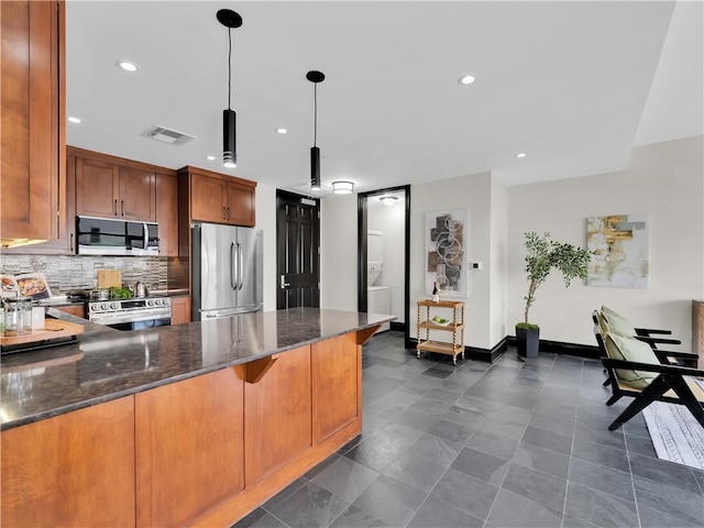 401 W Watson St Unit 507, Fayetteville, AR 72701 - kitchen featuring appliances with stainless steel finishes, dark stone countertops, a peninsula, brown cabinetry, and recessed lighting