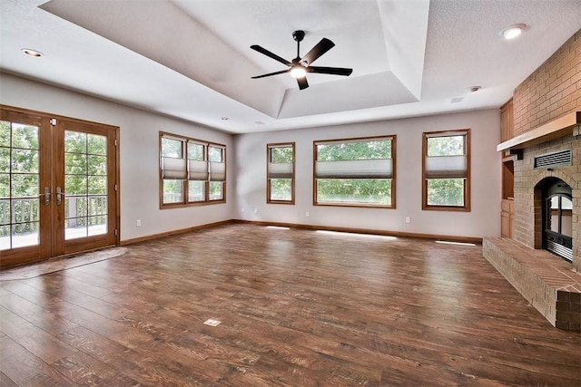 1 May Ln, Bella Vista, AR 72715 - unfurnished living room featuring a brick fireplace, hardwood / wood-style floors, a tray ceiling, and plenty of natural light