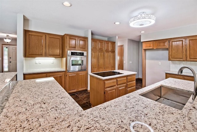 1 May Ln, Bella Vista, AR 72715 - kitchen with stainless steel oven, black electric stovetop, brown cabinets, light stone countertops, and recessed lighting