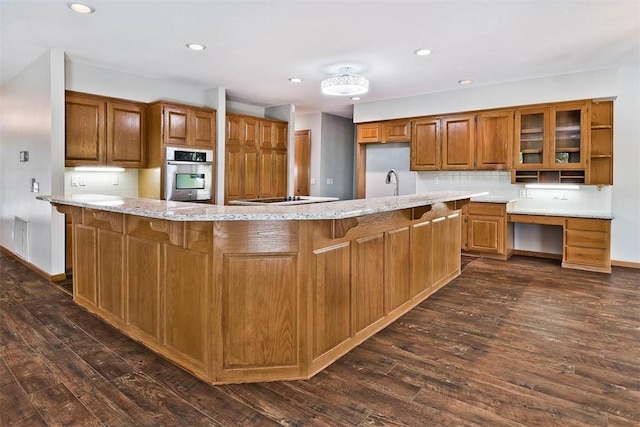 1 May Ln, Bella Vista, AR 72715 - kitchen featuring oven, brown cabinets, dark wood-style flooring, light stone counters, and recessed lighting
