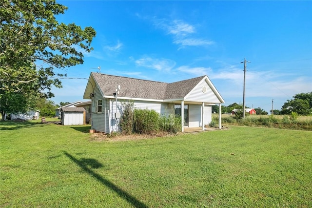 13183 Shady Grove Rd, Gravette, AR 72736 - back of house with a lawn, roof with shingles, and a storage unit
