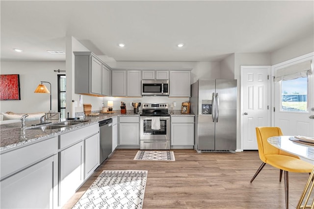 3461 Red Tail Way, Farmington, AR 72730 - kitchen featuring stainless steel appliances, light stone countertops, gray cabinets, light wood-style floors, and recessed lighting