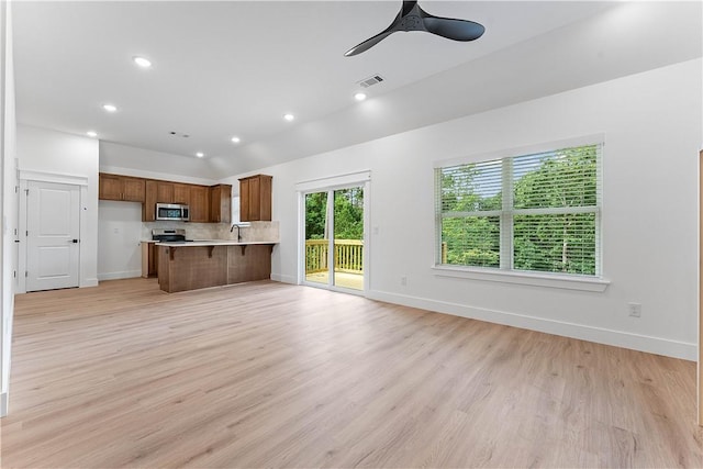 127 Overton Dr, Bella Vista, AR 72714 - kitchen with stainless steel microwave, brown cabinetry, light countertops, a peninsula, and open floor plan