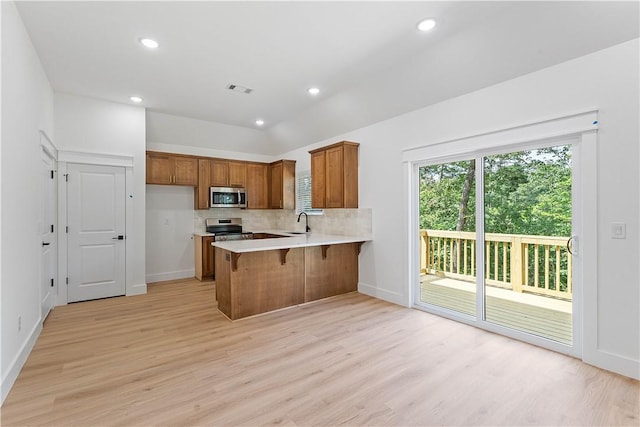 127 Overton Dr, Bella Vista, AR 72714 - kitchen with stainless steel appliances, brown cabinetry, a peninsula, light wood-type flooring, and light countertops