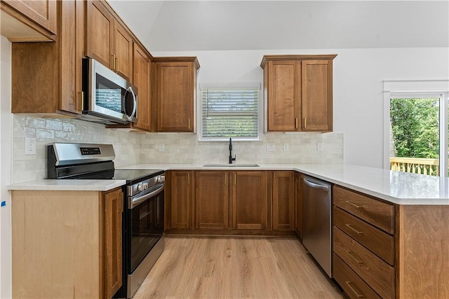 127 Overton Dr, Bella Vista, AR 72714 - kitchen featuring appliances with stainless steel finishes, a peninsula, light wood-style flooring, and brown cabinetry