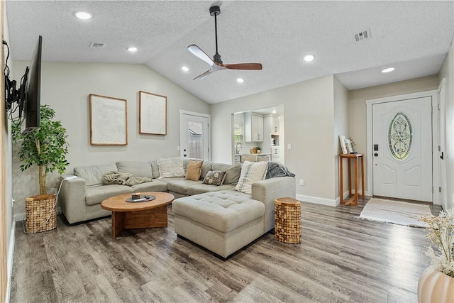 2905 NE 12th St, Bentonville, AR 72712 - living room with light wood-style floors, ceiling fan, vaulted ceiling, a textured ceiling, and recessed lighting