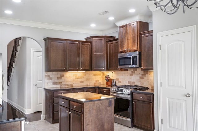 3915 Baltic St, Springdale, AR 72762 - kitchen with stainless steel appliances, dark countertops, a kitchen island, decorative backsplash, and ornamental molding