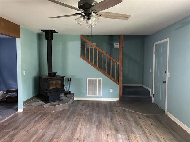 80 County Road 2560, Eureka Springs, AR 72631 - unfurnished living room featuring wood finished floors, stairway, a wood stove, and ceiling fan