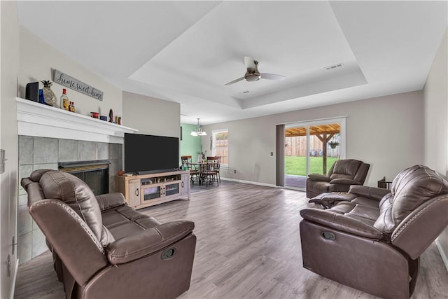 2317 SW Morris St, Bentonville, AR 72712 - living area with a tray ceiling, a ceiling fan, wood finished floors, and a tiled fireplace