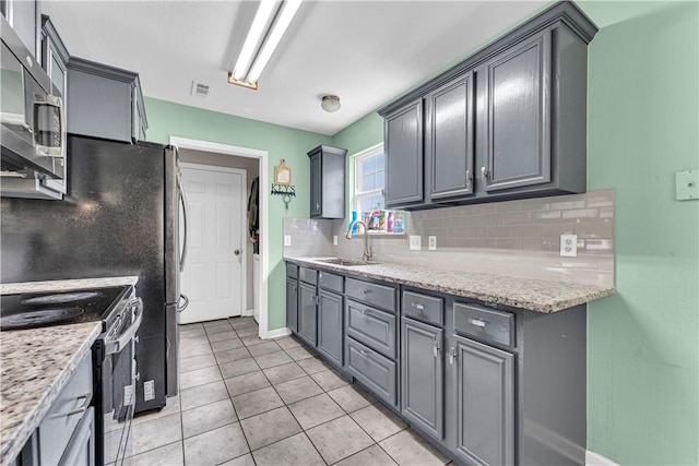 2317 SW Morris St, Bentonville, AR 72712 - kitchen with appliances with stainless steel finishes, backsplash, light tile patterned floors, light stone counters, and gray cabinets