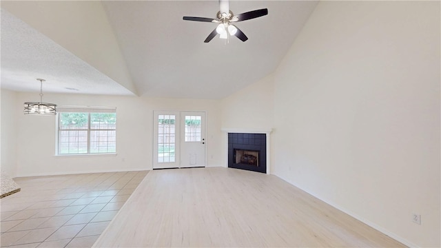 1142 S Jasmine Ln, Fayetteville, AR 72704 - unfurnished living room with a fireplace, ceiling fan, light wood-style flooring, high vaulted ceiling, and a chandelier
