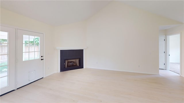 1142 S Jasmine Ln, Fayetteville, AR 72704 - unfurnished living room featuring light wood-type flooring, a tile fireplace, and vaulted ceiling