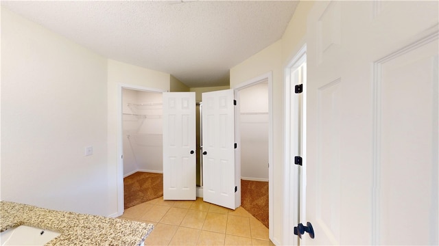 1142 S Jasmine Ln, Fayetteville, AR 72704 - bathroom with tile patterned flooring, a walk in closet, and a textured ceiling