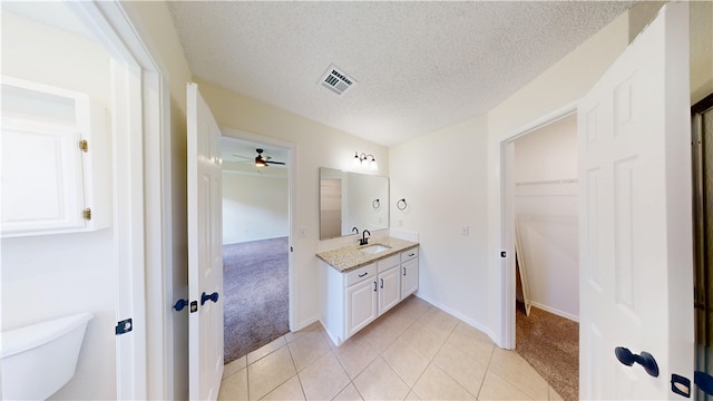1142 S Jasmine Ln, Fayetteville, AR 72704 - bathroom with vanity, ceiling fan, a walk in closet, tile patterned flooring, and a textured ceiling