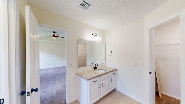 1142 S Jasmine Ln, Fayetteville, AR 72704 - bathroom with vanity, a ceiling fan, a walk in closet, and a textured ceiling
