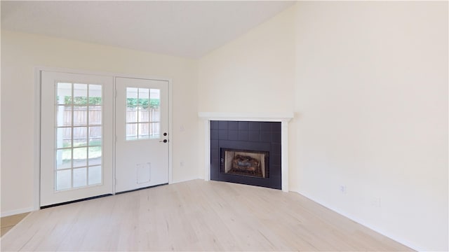 1142 S Jasmine Ln, Fayetteville, AR 72704 - unfurnished living room featuring wood finished floors, a tiled fireplace, and lofted ceiling