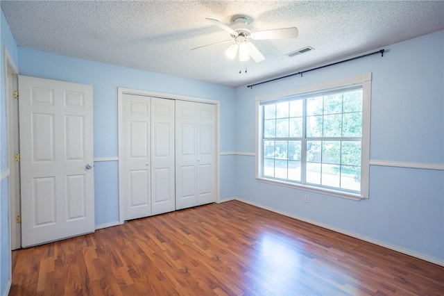 2472 W Jane Circle Dr, Fayetteville, AR 72704 - unfurnished bedroom featuring wood finished floors, a textured ceiling, a closet, and a ceiling fan
