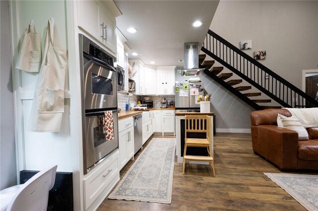 19475 Cotton Ln, Garfield, AR 72732 - kitchen with appliances with stainless steel finishes, open floor plan, dark wood-type flooring, tasteful backsplash, and white cabinets
