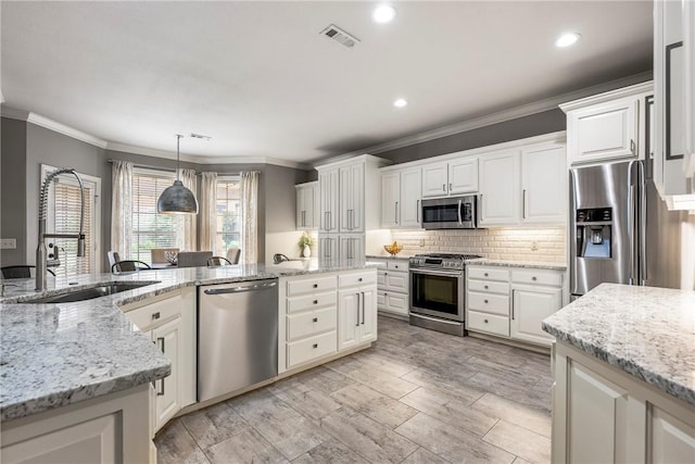 5503 S Turnberry Rd, Rogers, AR 72758 - kitchen with appliances with stainless steel finishes, pendant lighting, ornamental molding, tasteful backsplash, and white cabinets