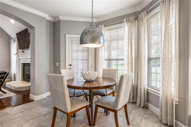 5503 S Turnberry Rd, Rogers, AR 72758 - dining room featuring arched walkways, light wood-style floors, a tiled fireplace, and ornamental molding