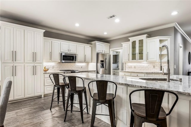 5503 S Turnberry Rd, Rogers, AR 72758 - kitchen with appliances with stainless steel finishes, a breakfast bar, white cabinetry, decorative backsplash, and crown molding