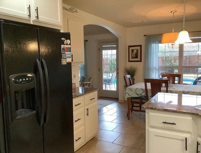 3809 N 2nd Pl, Rogers, AR 72756 - kitchen with black fridge with ice dispenser, arched walkways, plenty of natural light, and stone countertops